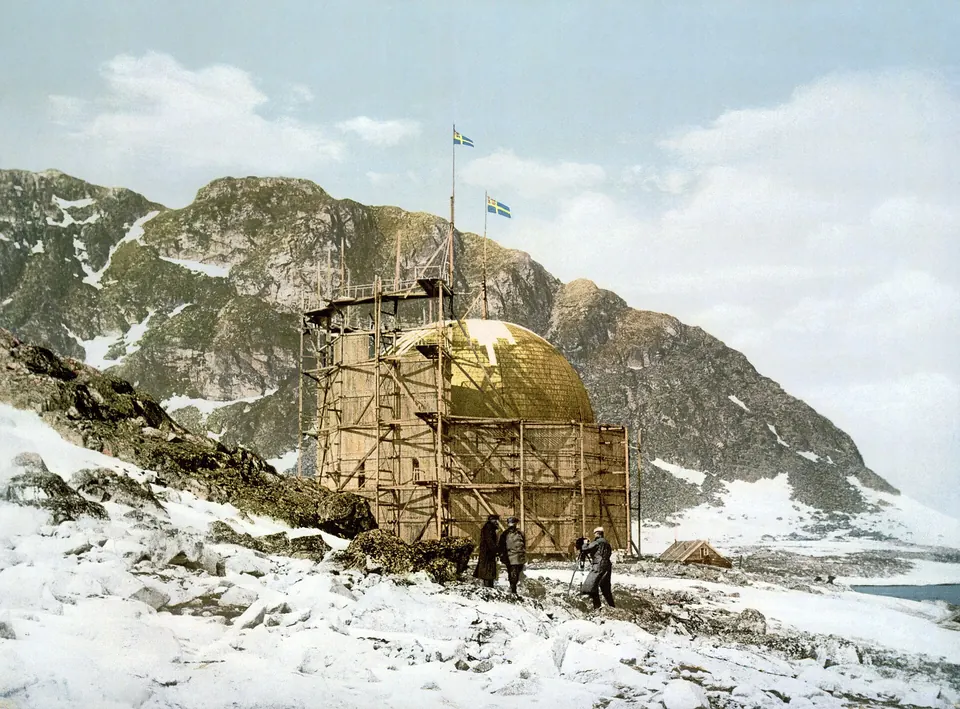 Historiallinen, jälkikäteen väritetty valokuva Andréen pallohallista Danskøyalla Ruotsin lipun kanssa