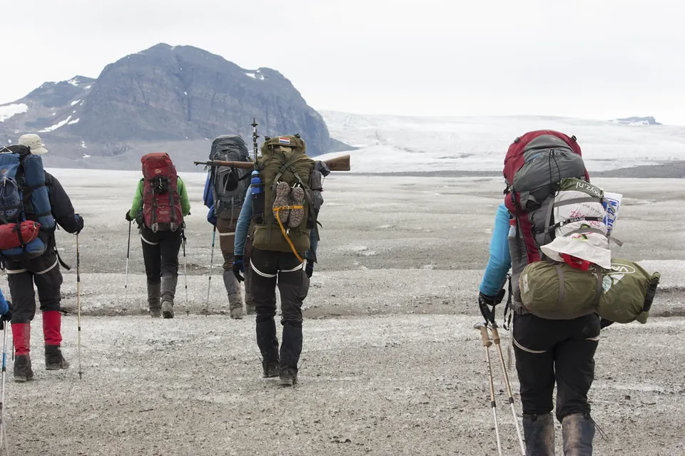 Gruppe von Wanderern mit Rucksäcken auf einem Gletscher auf Spitzbergen