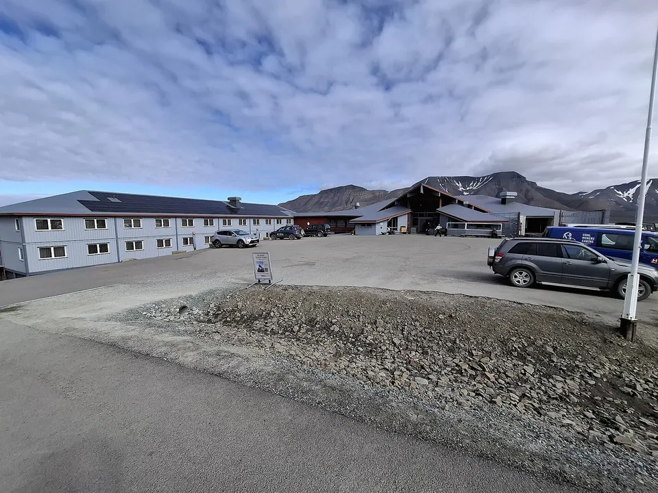 Hotelgebäude in Longyearbyen mit Schnee und Bergen im Hintergrund