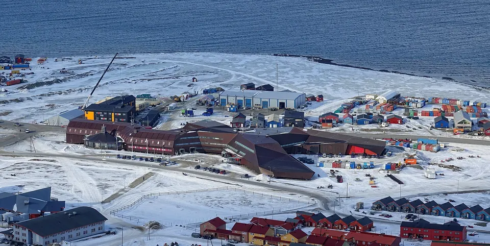 Longyearbyenin värikkäät puutalot laaksossa, lumiset tunturit ja Adventfjorden taustalla