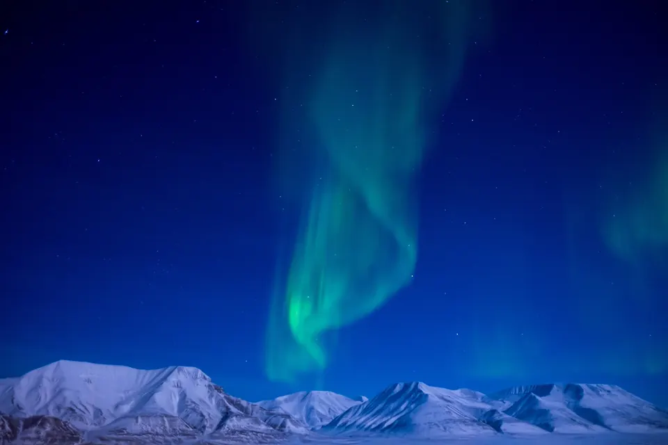 Groen noorderlicht boven besneeuwde bergen op Spitsbergen