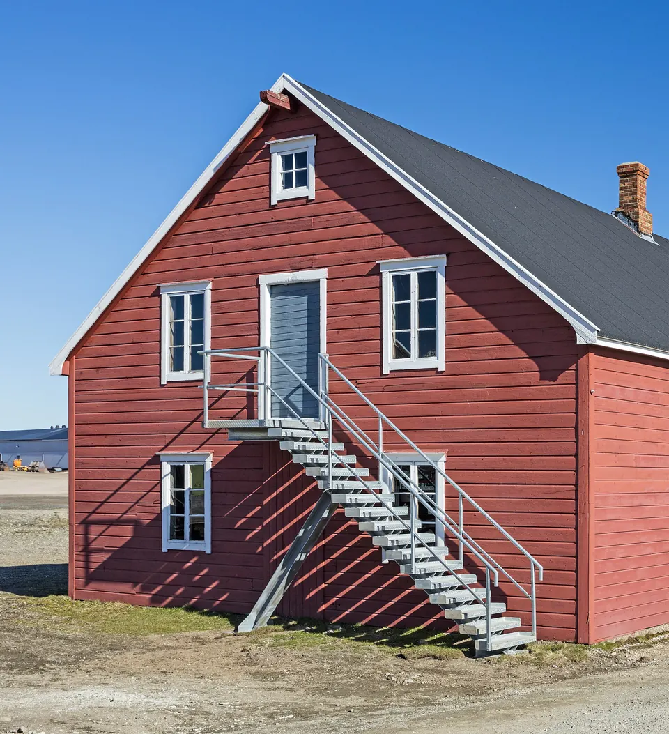 Punainen puutalo, jossa on museo, Ny-Ålesundissa sinisen taivaan alla