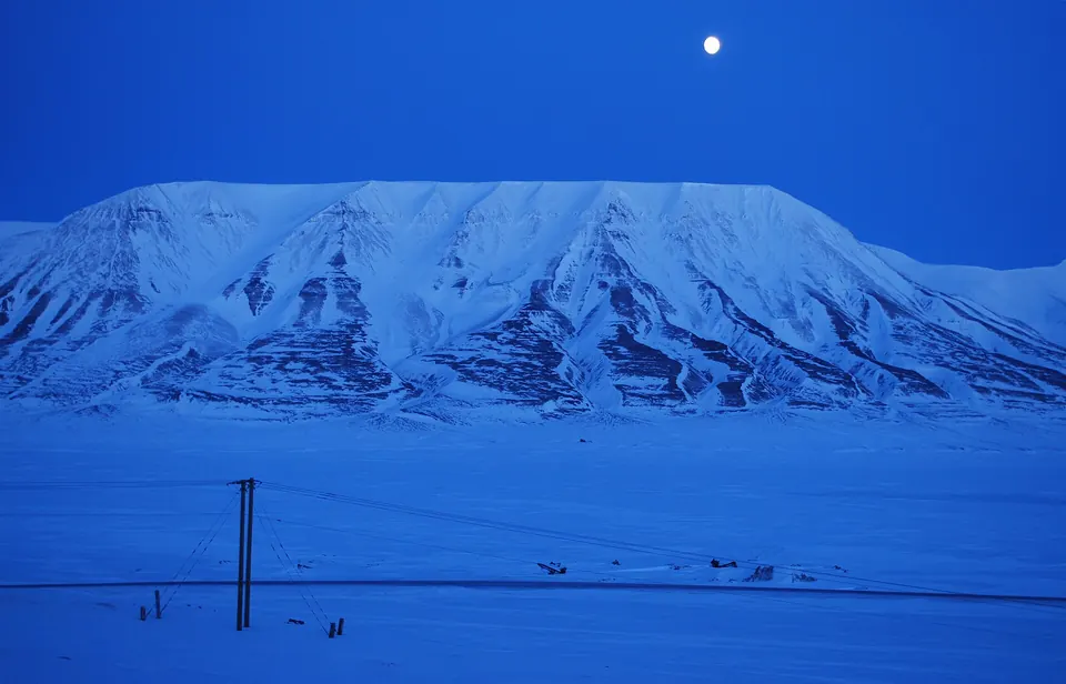 Blauw licht van de donkere tijd boven besneeuwde bergen en de Adventfjord bij Longyearbyen