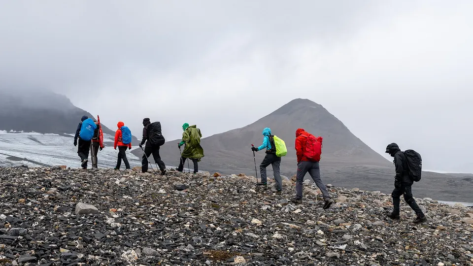 Wandelaars in regenkleding op stenig terrein op Spitsbergen
